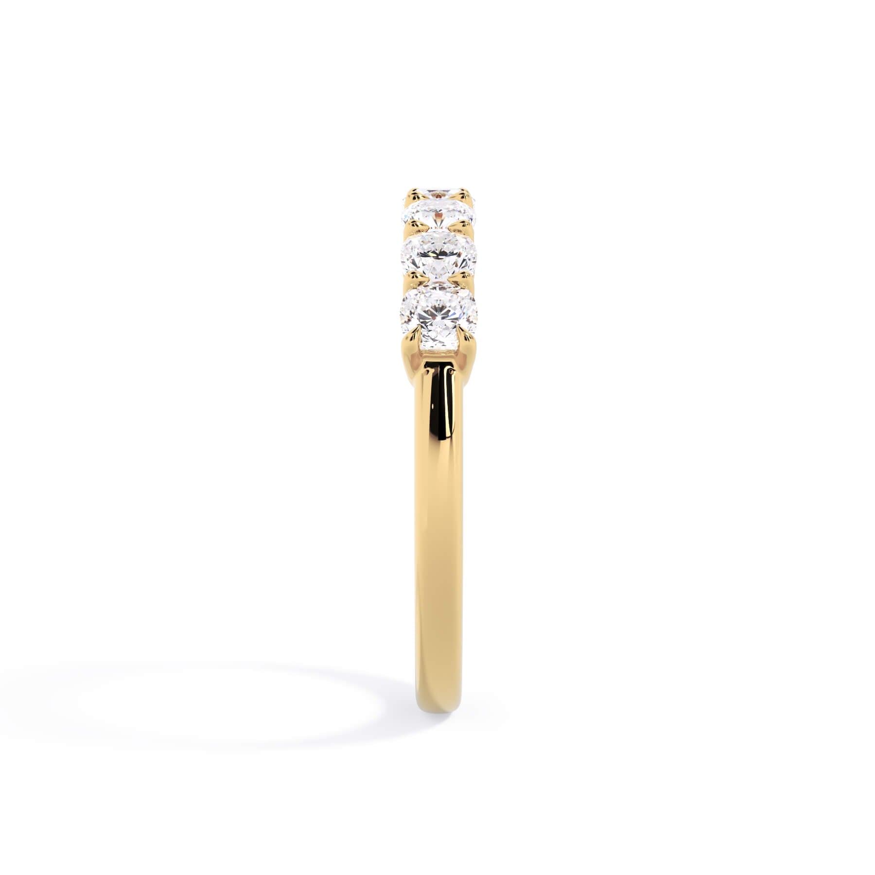 A picture of a seven stone diamond wedding ring with cushion cut diamonds that are shared prong set in yellow gold on a white background with a side profile view.