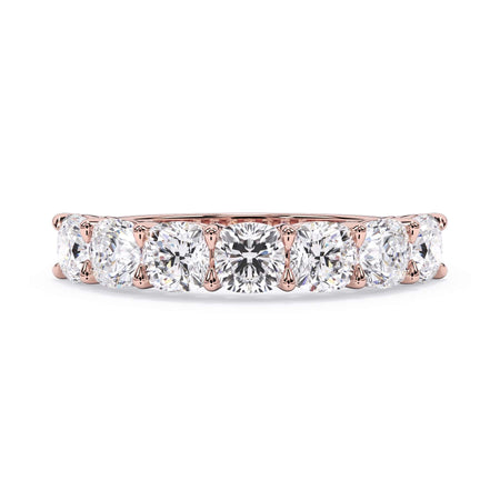 A picture of a seven stone diamond wedding ring with cushion cut diamonds that are shared prong set in rose gold on a white background with the ring facing forward, lying down.