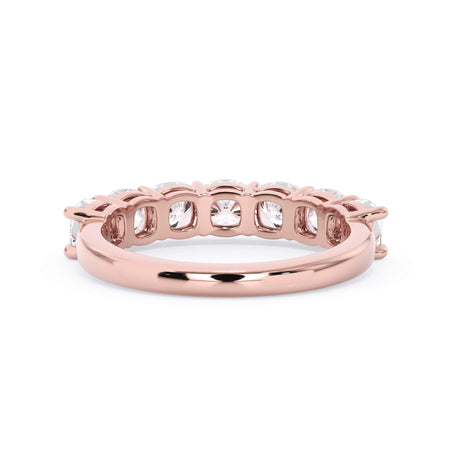 A picture of a seven stone diamond wedding ring with cushion cut diamonds that are shared prong set in rose gold on a white background with a view of the underside of the ring.