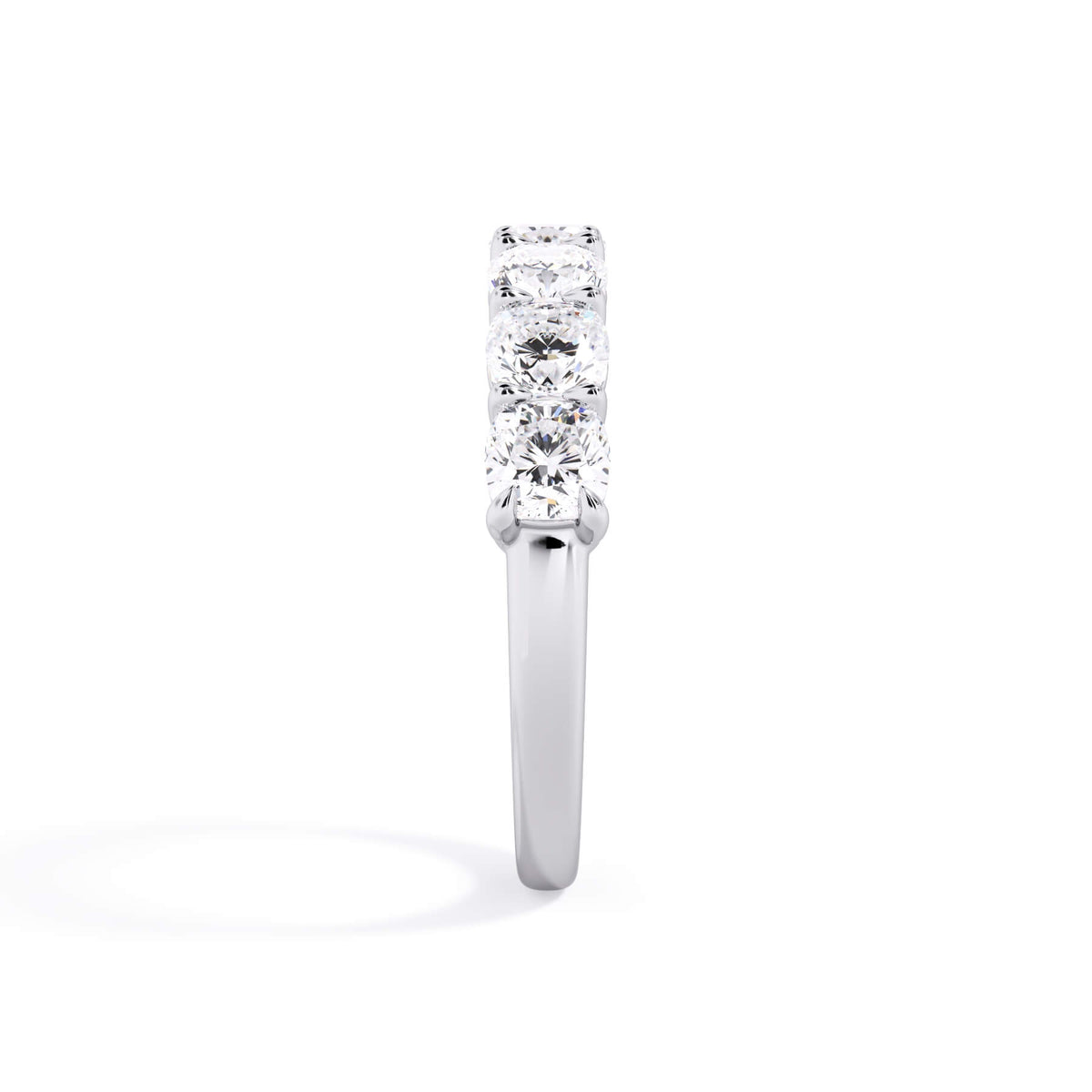 A picture of a seven stone diamond wedding ring with cushion cut diamonds that are shared prong set in white gold or platinum on a white background with a side profile view.