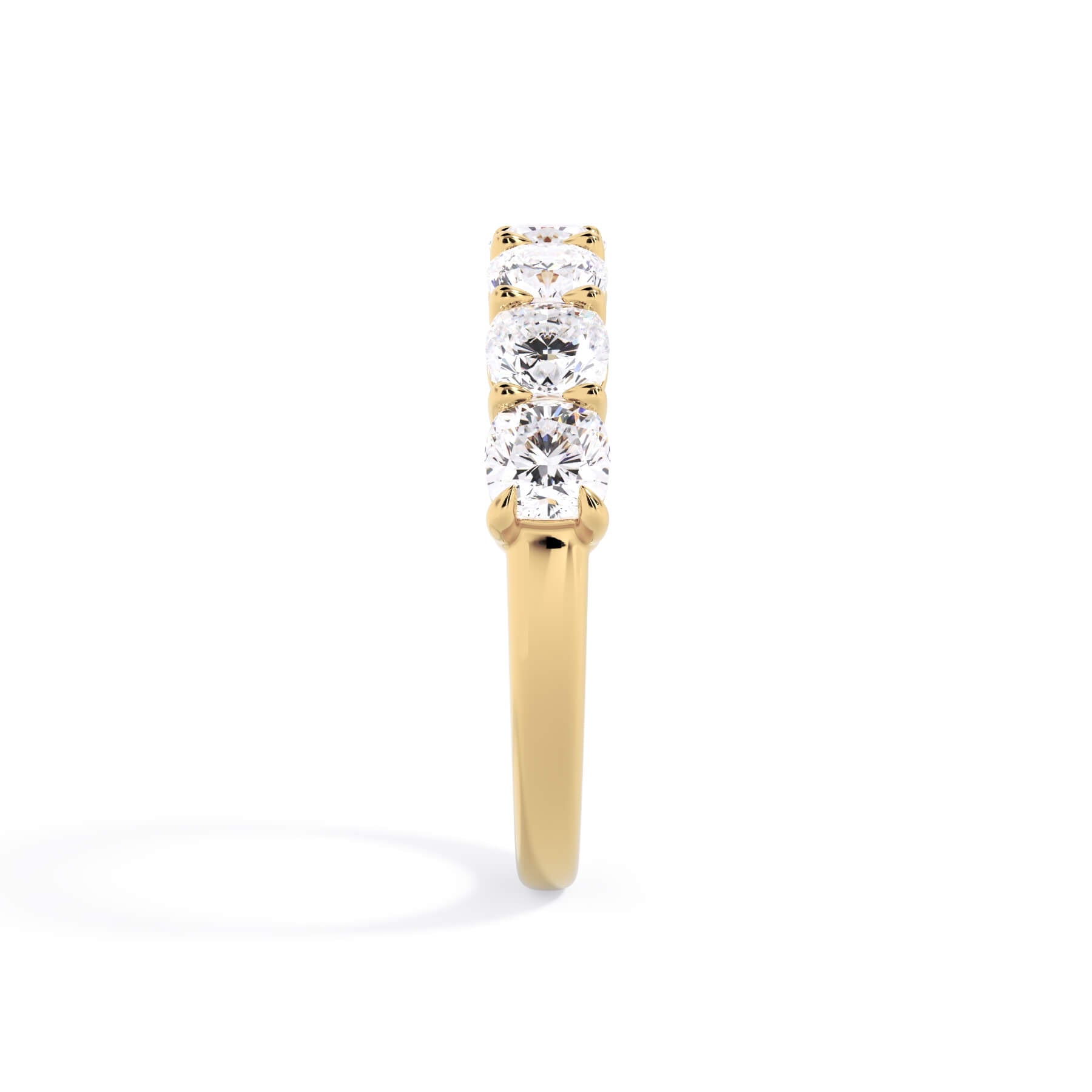 A picture of a seven stone diamond wedding ring with cushion cut diamonds that are shared prong set in yellow gold on a white background with a side profile view.