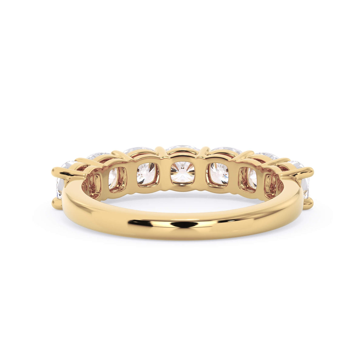 A picture of a seven stone diamond wedding ring with cushion cut diamonds that are shared prong set in yellow gold on a white background with a view of the underside of the ring.