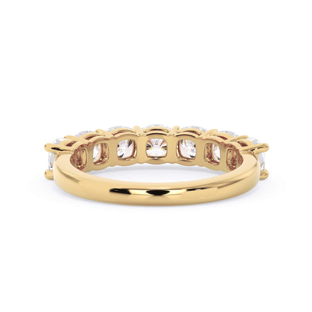 A picture of a seven stone diamond wedding ring with cushion cut diamonds that are shared prong set in yellow gold on a white background with a view of the underside of the ring.
