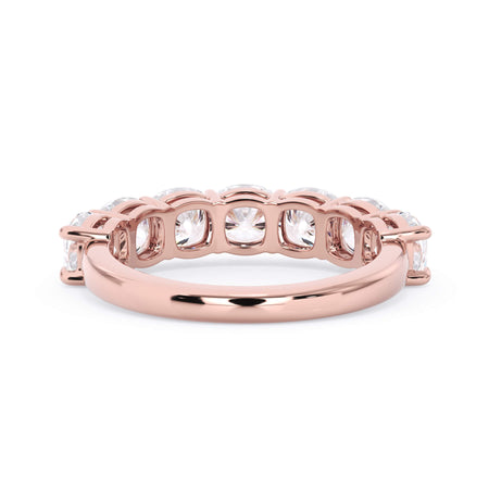 A picture of a seven stone diamond wedding ring with cushion cut diamonds that are shared prong set in rose gold on a white background with a view of the underside of the ring.