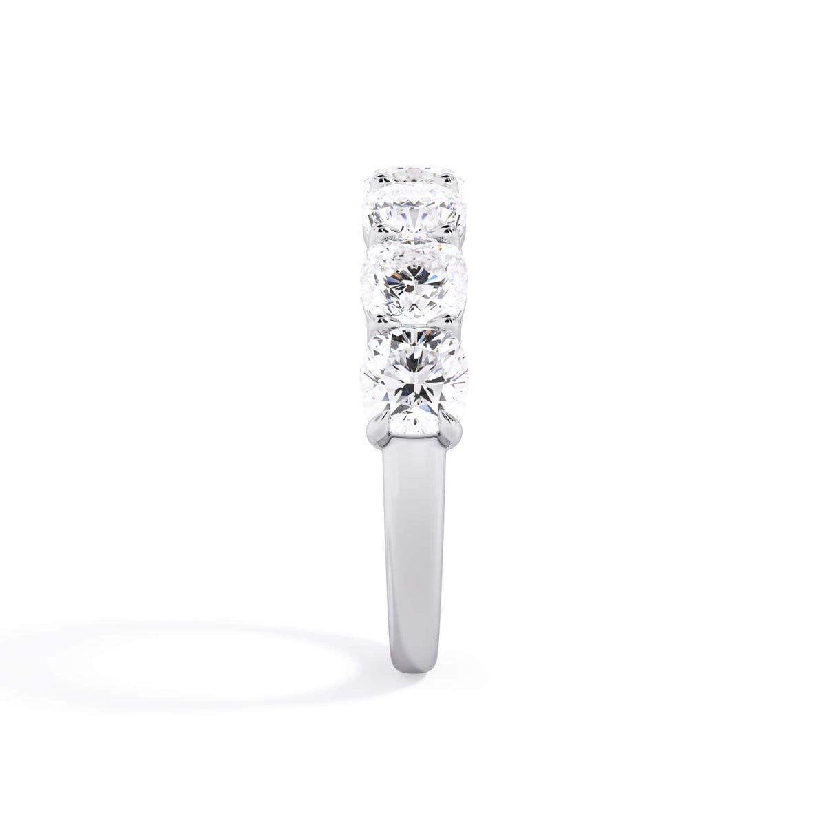 A picture of a seven stone diamond wedding ring with cushion cut diamonds that are shared prong set in white gold or platinum on a white background with a side profile view.