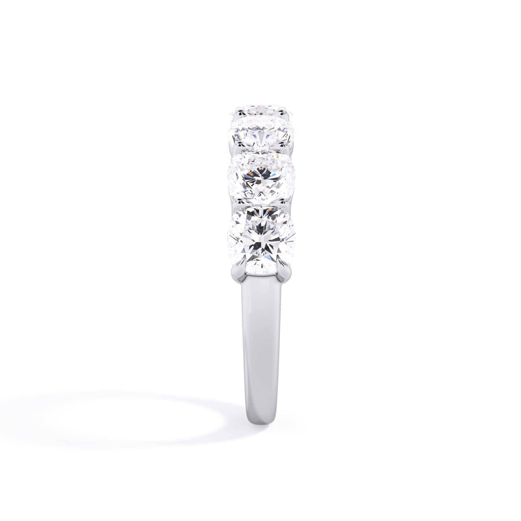 A picture of a seven stone diamond wedding ring with cushion cut diamonds that are shared prong set in white gold or platinum on a white background with a side profile view.