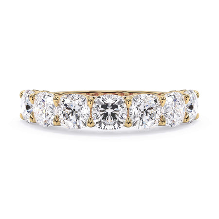 A picture of a seven stone diamond wedding ring with cushion cut diamonds that are shared prong set in yellow gold on a white background with the ring facing forward, lying down.