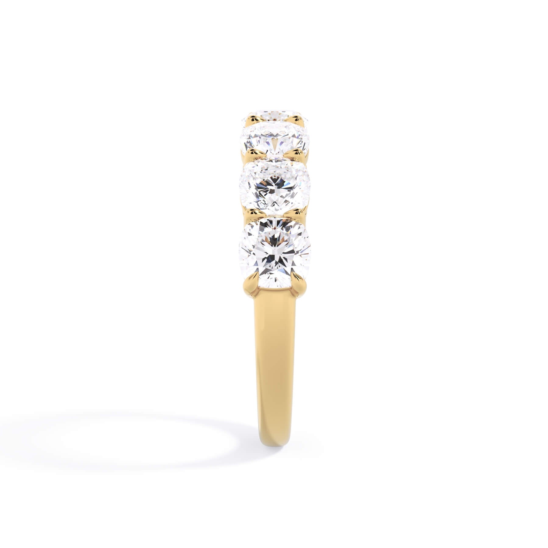A picture of a seven stone diamond wedding ring with cushion cut diamonds that are shared prong set in yellow gold on a white background with a side profile view.