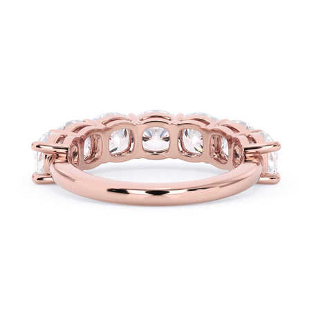 A picture of a seven stone diamond wedding ring with cushion cut diamonds that are shared prong set in rose gold on a white background with a view of the underside of the ring.