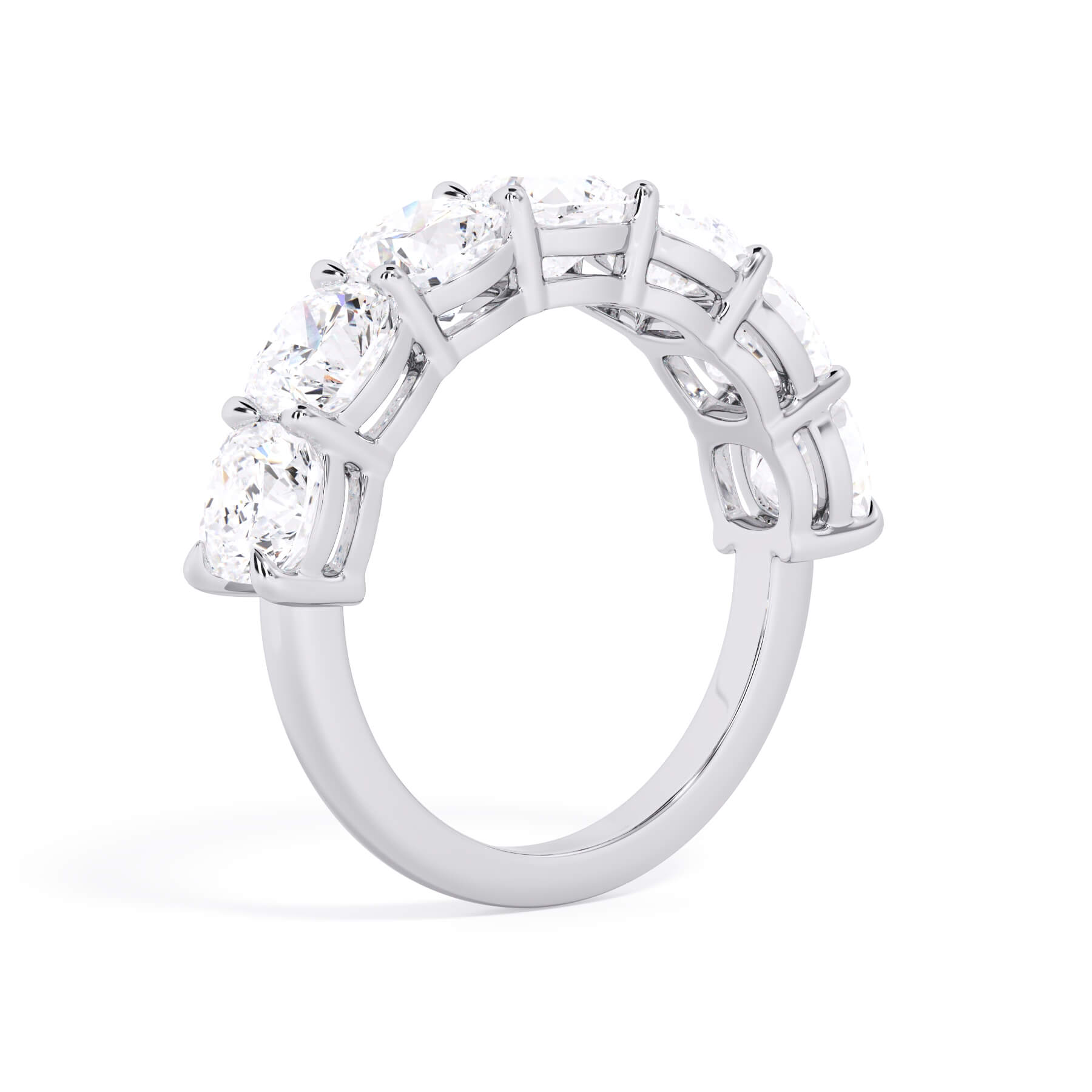 A picture of a seven stone diamond wedding ring with cushion cut diamonds that are shared prong set in white gold or platinum on a white background with a slightly angled, through the finger view.