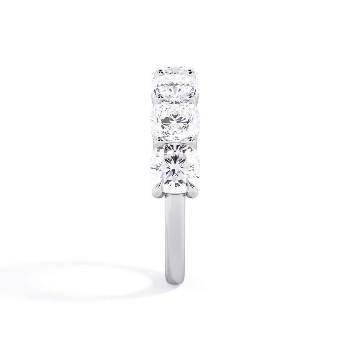 A picture of a seven stone diamond wedding ring with cushion cut diamonds that are shared prong set in white gold or platinum on a white background with a side profile view.
