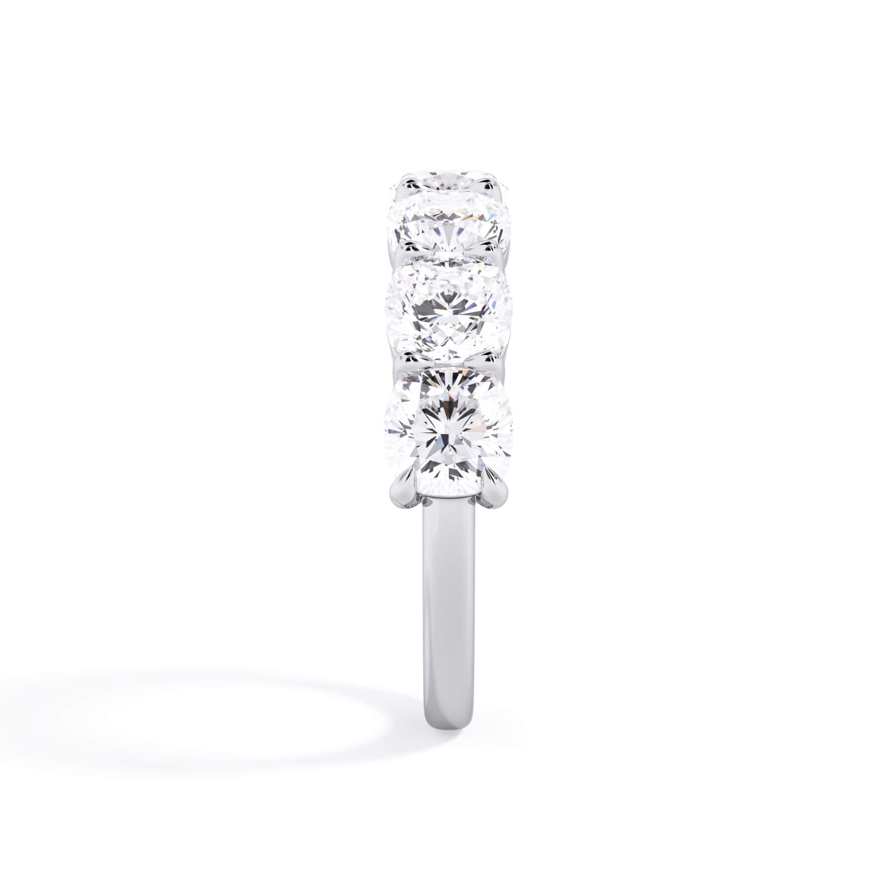 A picture of a seven stone diamond wedding ring with cushion cut diamonds that are shared prong set in white gold or platinum on a white background with a side profile view.