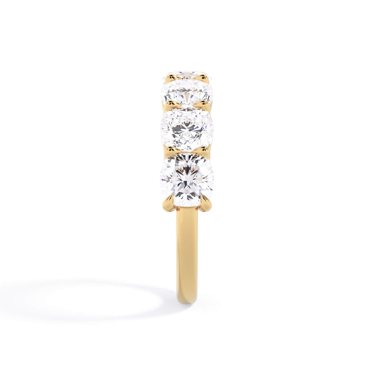 A picture of a seven stone diamond wedding ring with cushion cut diamonds that are shared prong set in yellow gold on a white background with a side profile view.