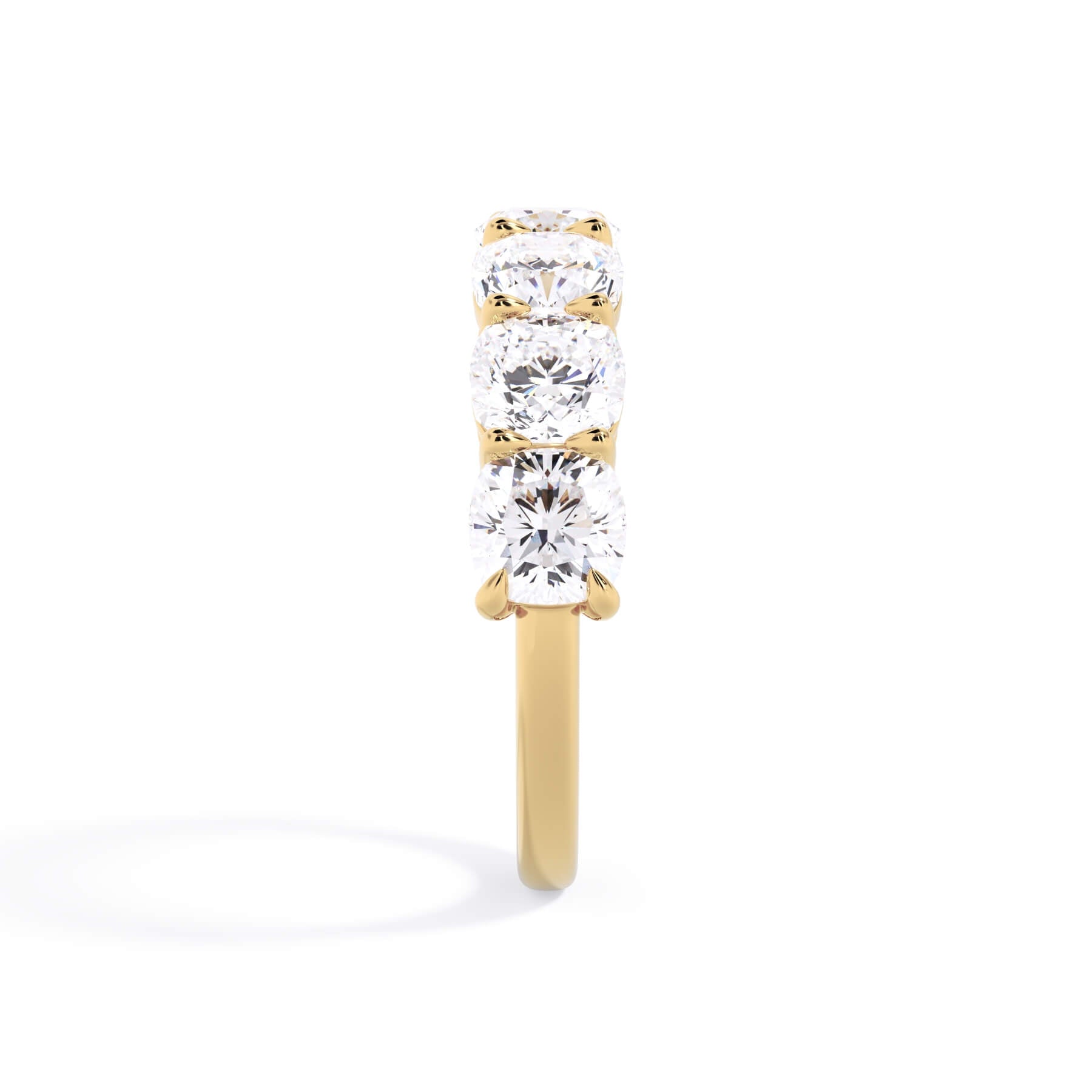 A picture of a seven stone diamond wedding ring with cushion cut diamonds that are shared prong set in yellow gold on a white background with a side profile view.