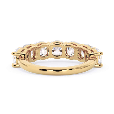 A picture of a seven stone diamond wedding ring with cushion cut diamonds that are shared prong set in yellow gold on a white background with a view of the underside of the ring.