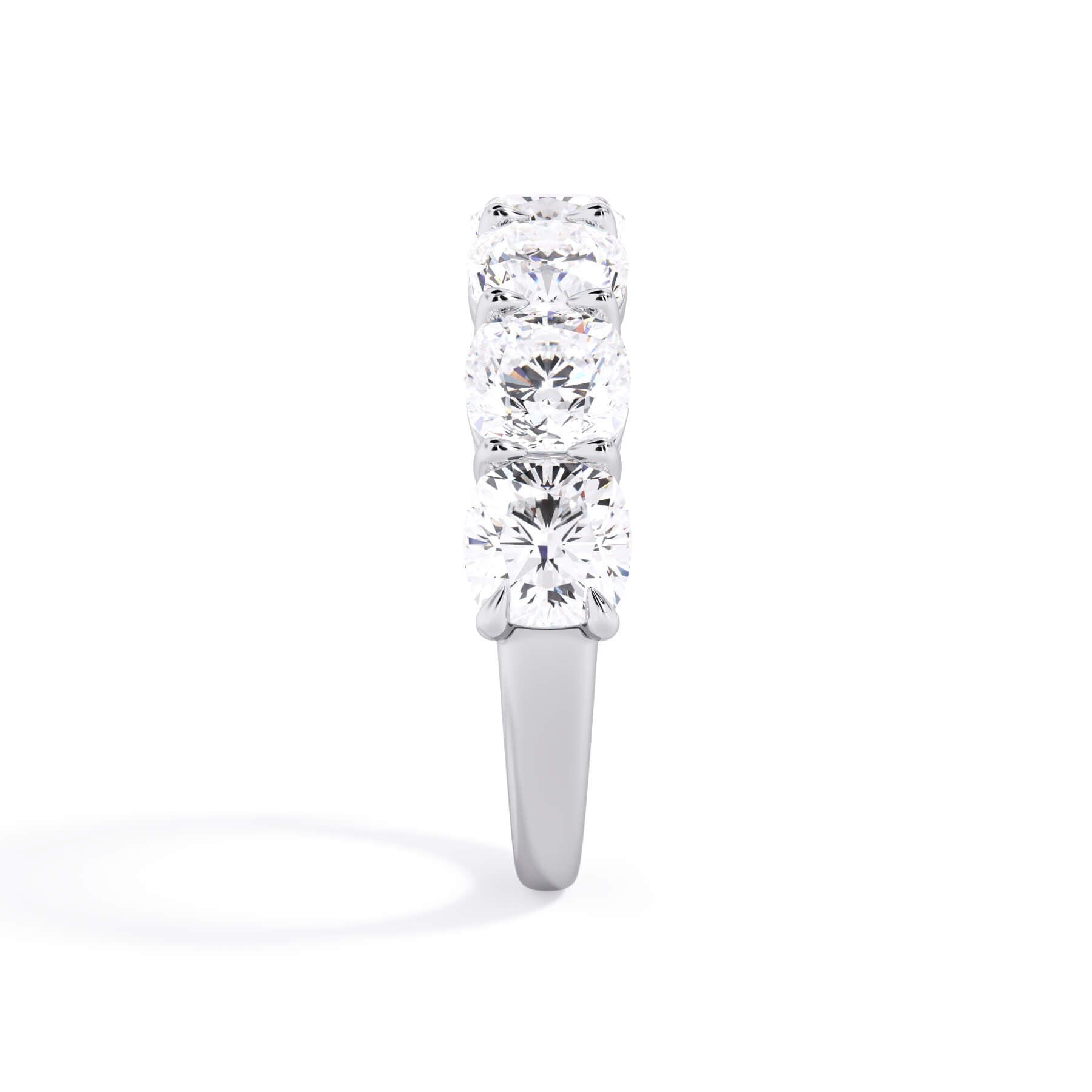 A picture of a seven stone diamond wedding ring with cushion cut diamonds that are shared prong set in white gold or platinum on a white background with a side profile view.