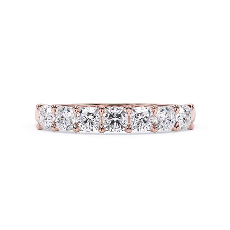 A picture of a seven stone diamond wedding ring with cushion cut diamonds that are U prong set in rose gold on a white background with the ring facing forward, lying down.