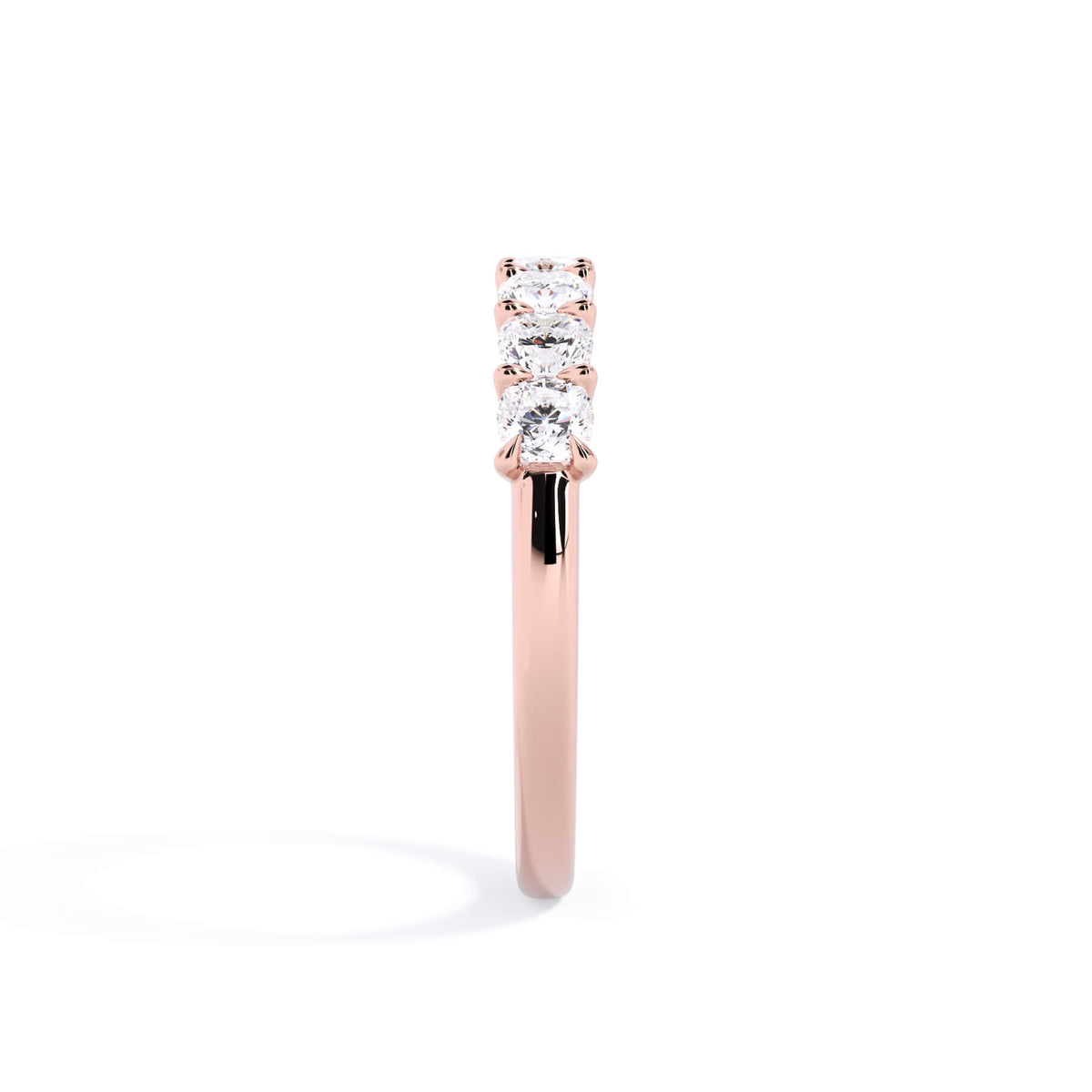 A picture of a seven stone diamond wedding ring with cushion cut diamonds that are U prong set in rose gold on a white background with a side profile view.
