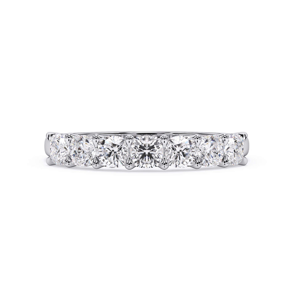 A picture of a seven stone diamond wedding ring with cushion cut diamonds that are U prong set in white gold or platinum on a white background with the ring facing forward, lying down.