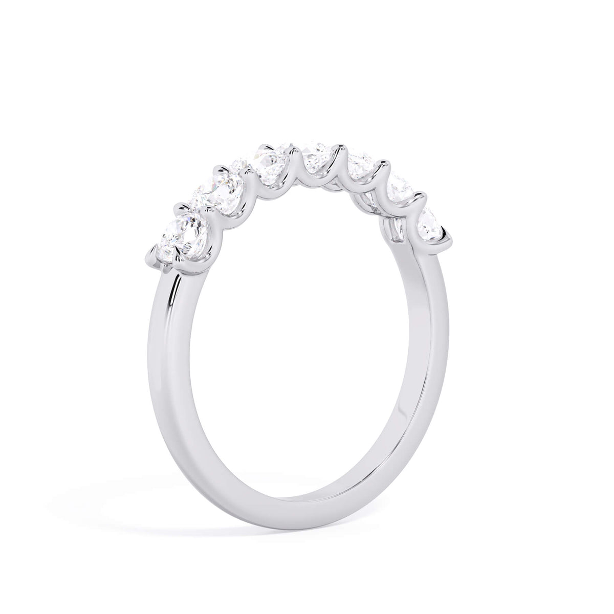 A picture of a seven stone diamond wedding ring with cushion cut diamonds that are U prong set in white gold or platinum on a white background with a slightly angled, through the finger view.