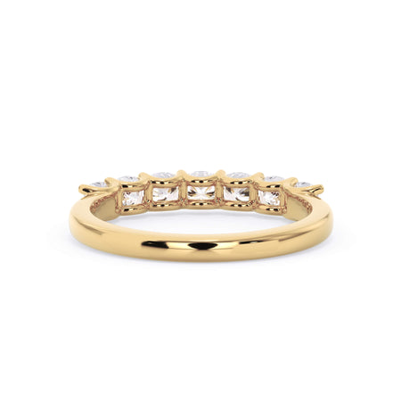 A picture of a seven stone diamond wedding ring with cushion cut diamonds that are U prong set in yellow gold on a white background with a view of the underside of the ring.