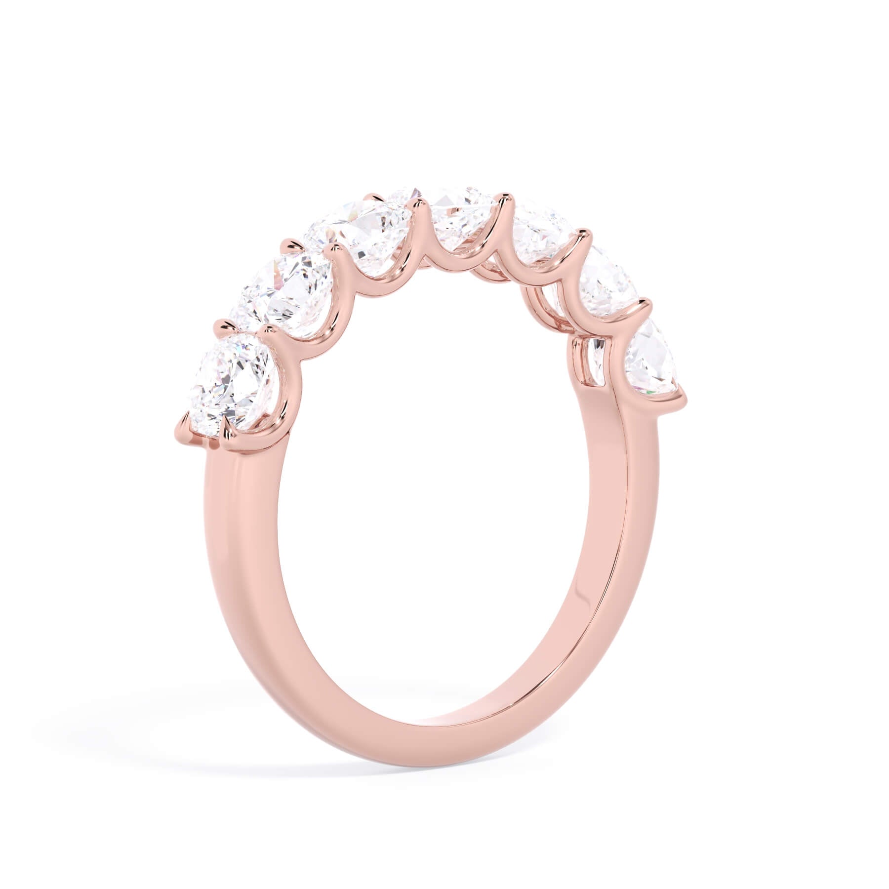A picture of a seven stone diamond wedding ring with cushion cut diamonds that are U prong set in rose gold on a white background with a slightly angled, through the finger view.