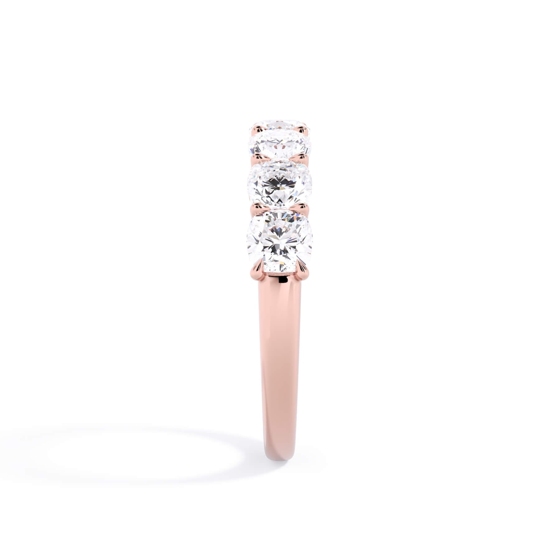 A picture of a seven stone diamond wedding ring with cushion cut diamonds that are U prong set in rose gold on a white background with a side profile view.
