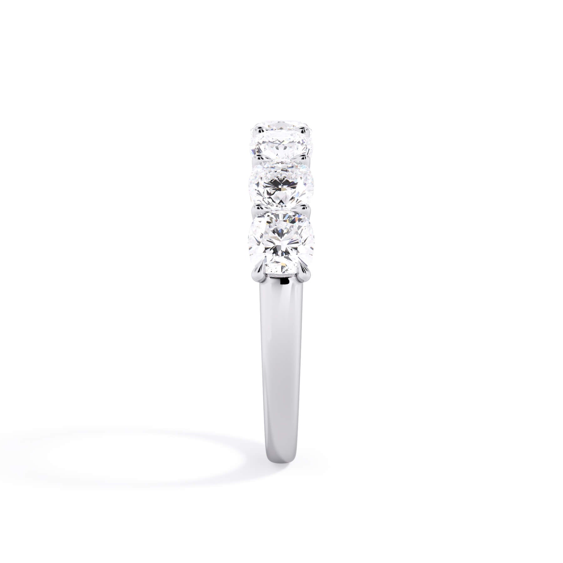 A picture of a seven stone diamond wedding ring with cushion cut diamonds that are U prong set in white gold or platinum on a white background with a side profile view.
