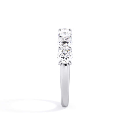 A picture of a seven stone diamond wedding ring with cushion cut diamonds that are U prong set in white gold or platinum on a white background with a side profile view.