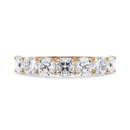 A picture of a seven stone diamond wedding ring with cushion cut diamonds that are U prong set in yellow gold on a white background with the ring facing forward, lying down.
