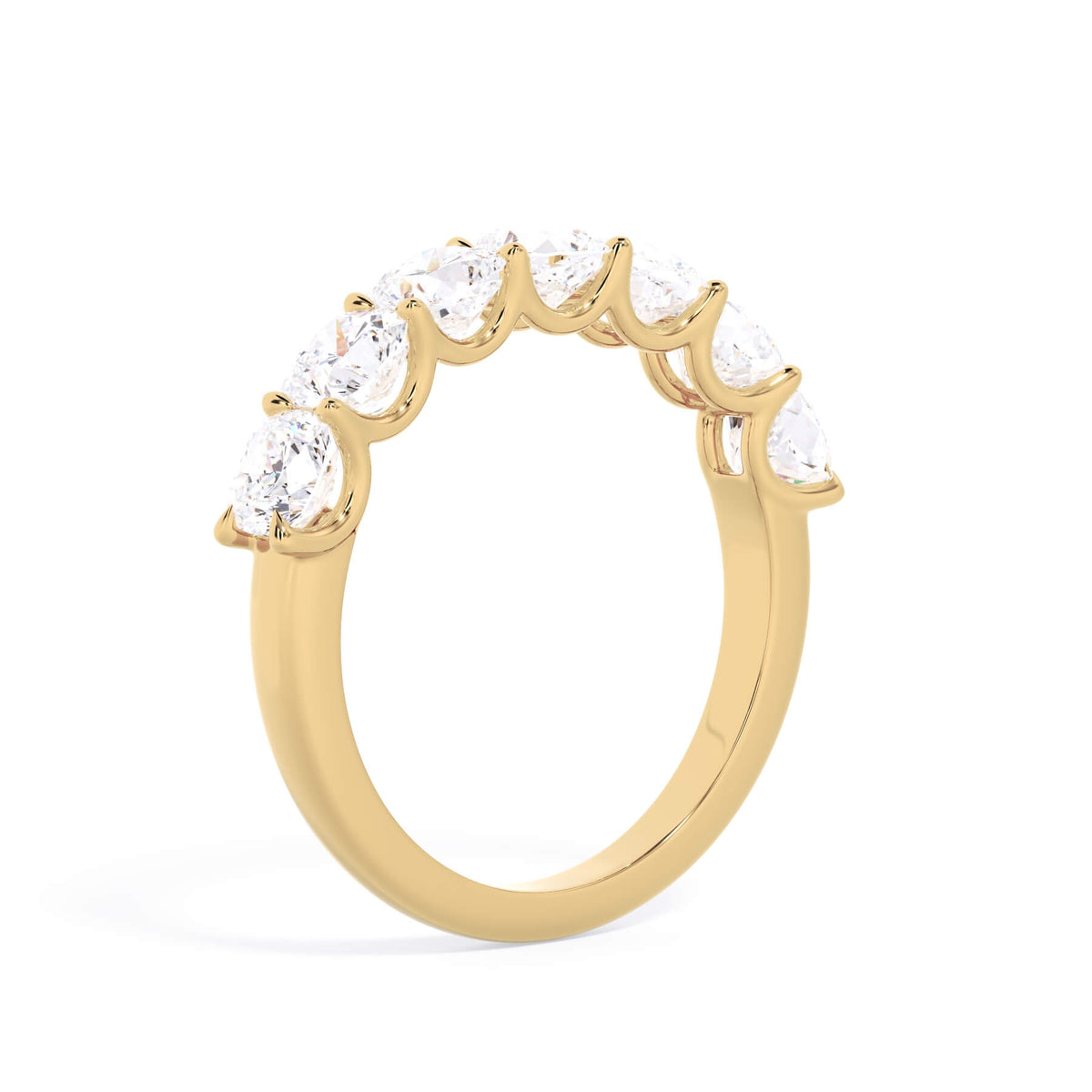 A picture of a seven stone diamond wedding ring with cushion cut diamonds that are U prong set in yellow gold on a white background with a slightly angled, through the finger view.