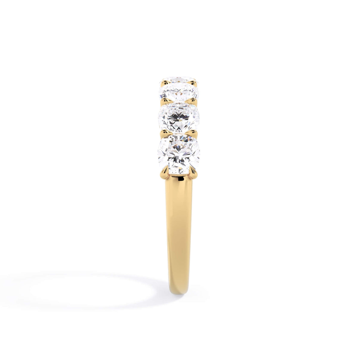 A picture of a seven stone diamond wedding ring with cushion cut diamonds that are U prong set in yellow gold on a white background with a side profile view.