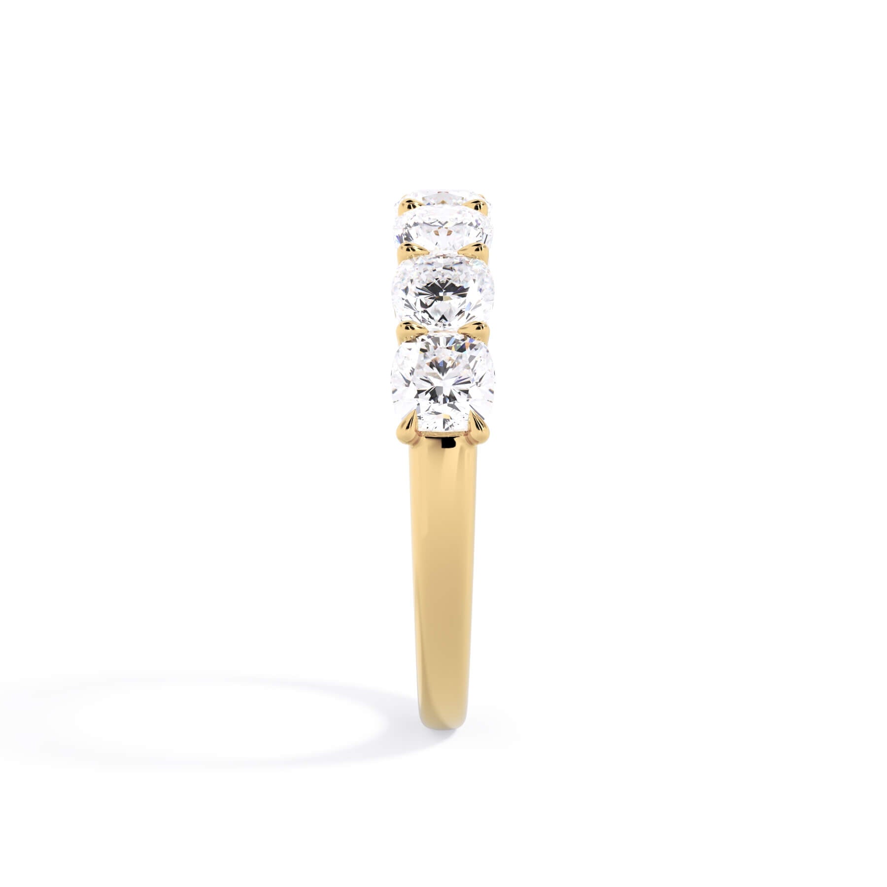 A picture of a seven stone diamond wedding ring with cushion cut diamonds that are U prong set in yellow gold on a white background with a side profile view.