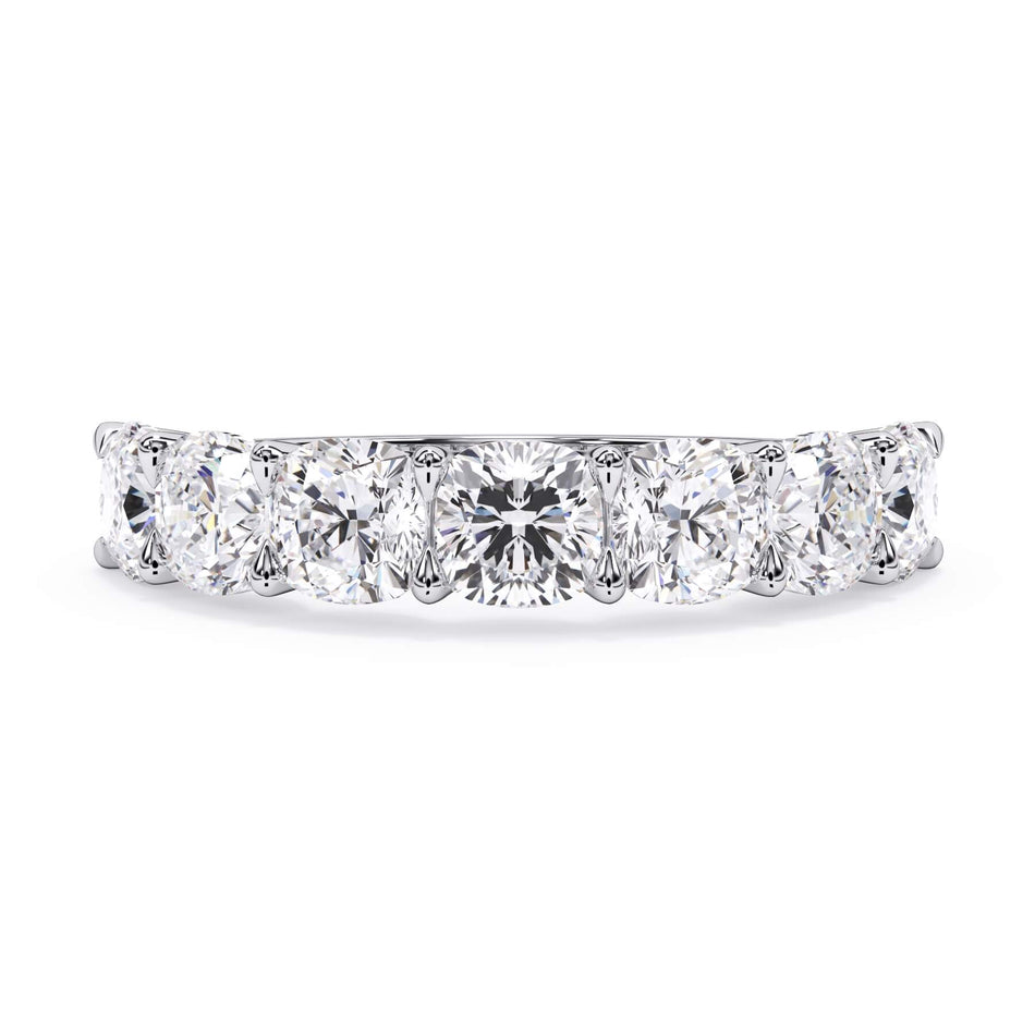 A picture of a seven stone diamond wedding ring with cushion cut diamonds that are U prong set in white gold or platinum on a white background with the ring facing forward, lying down.