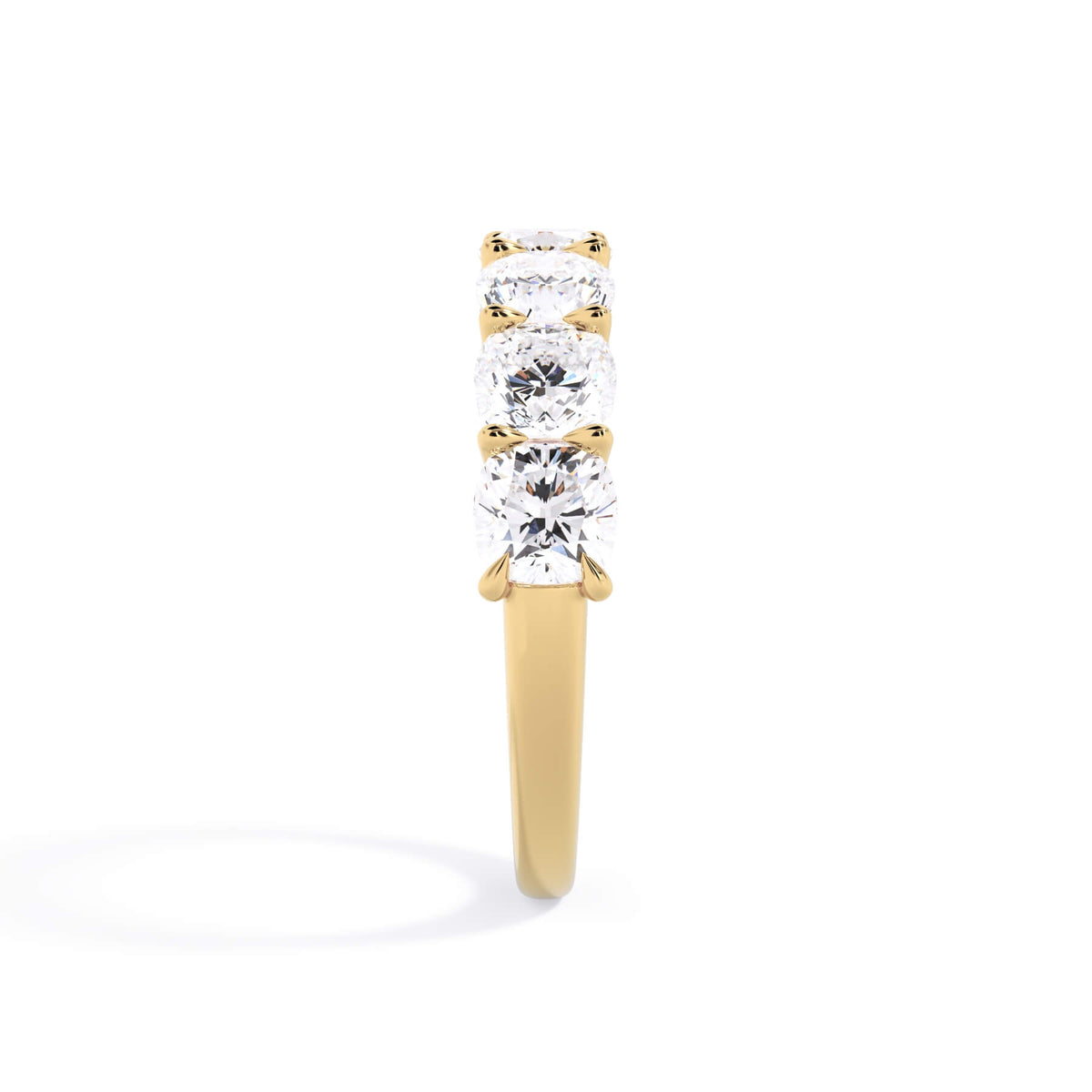 A picture of a seven stone diamond wedding ring with cushion cut diamonds that are U prong set in yellow gold on a white background with a side profile view.