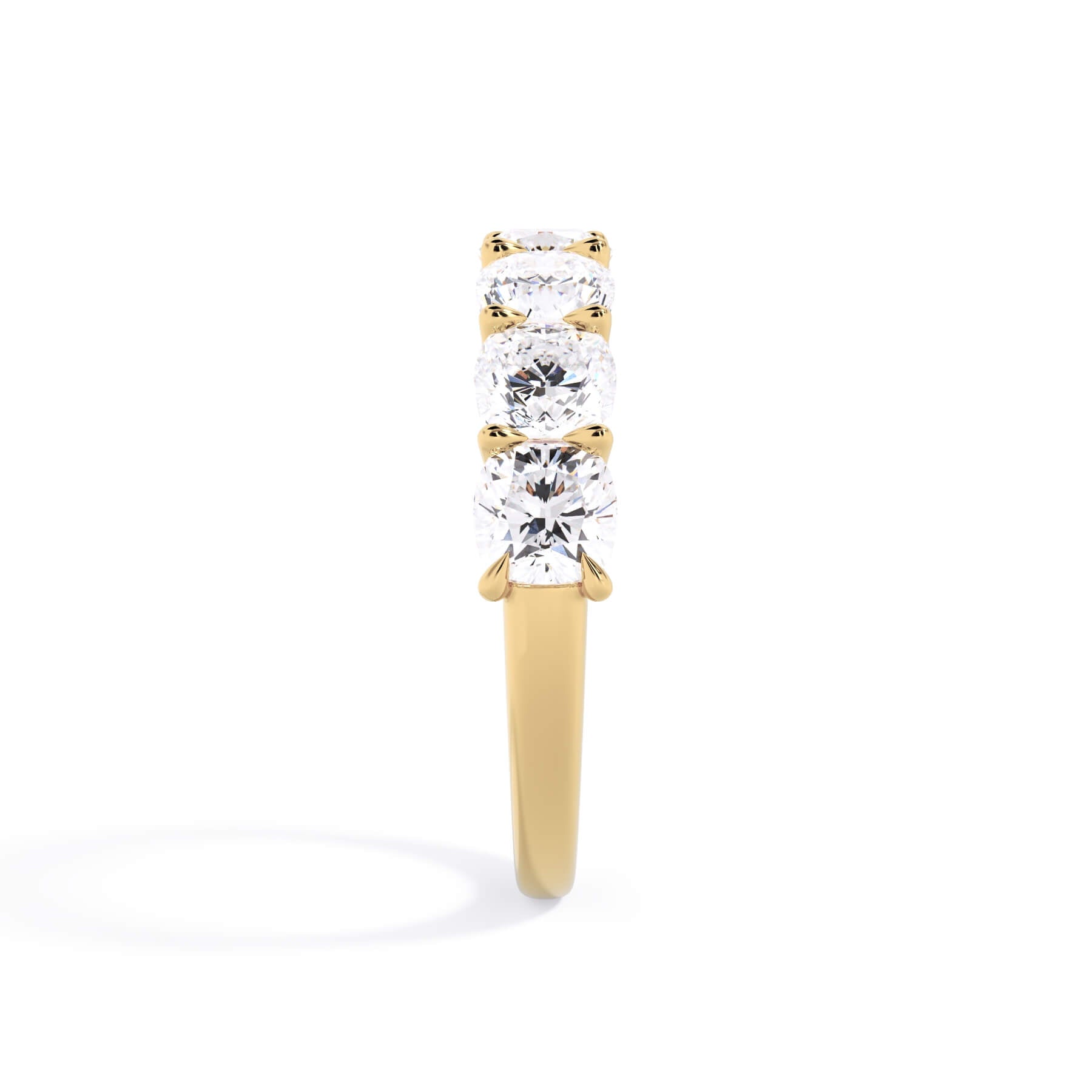 A picture of a seven stone diamond wedding ring with cushion cut diamonds that are U prong set in yellow gold on a white background with a side profile view.
