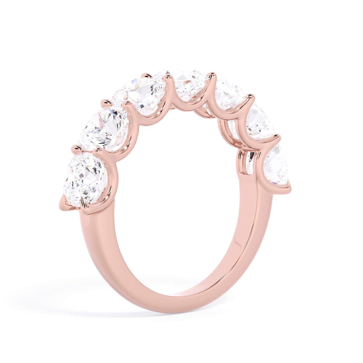A picture of a seven stone diamond wedding ring with cushion cut diamonds that are U prong set in rose gold on a white background with a slightly angled, through the finger view.