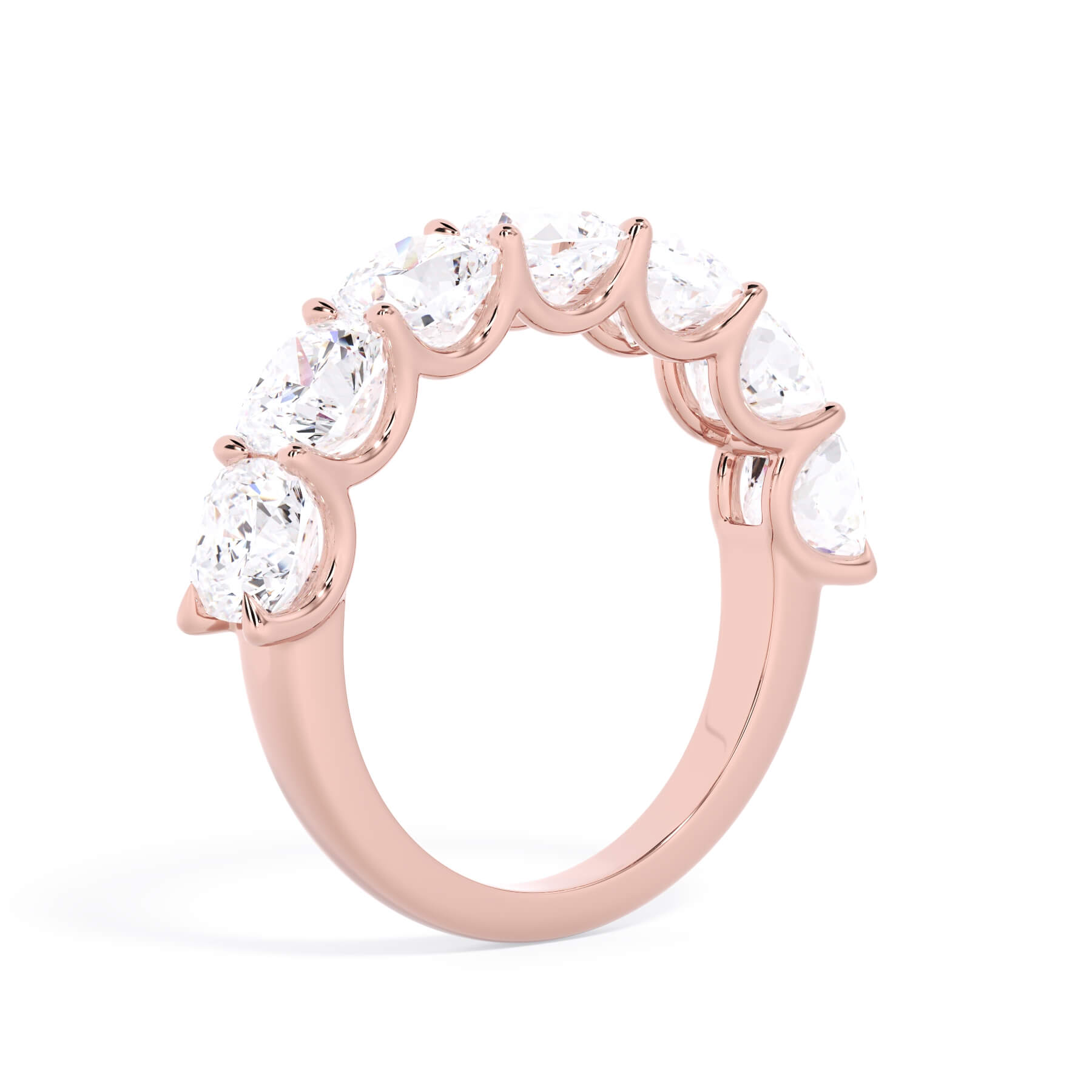 A picture of a seven stone diamond wedding ring with cushion cut diamonds that are U prong set in rose gold on a white background with a slightly angled, through the finger view.