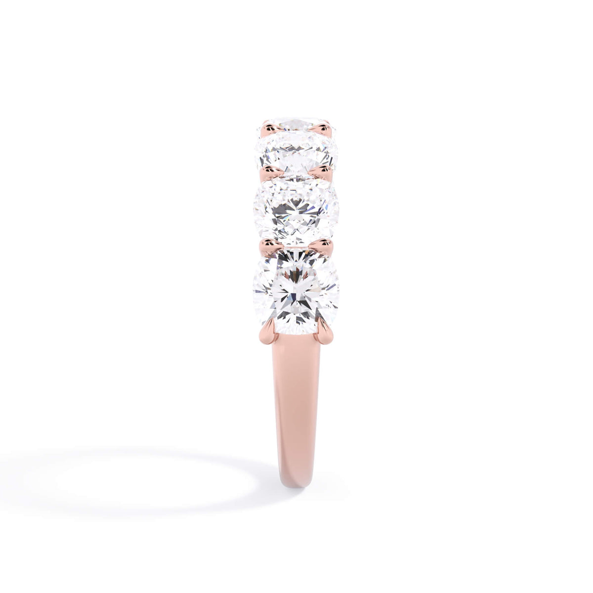 A picture of a seven stone diamond wedding ring with cushion cut diamonds that are U prong set in rose gold on a white background with a side profile view.
