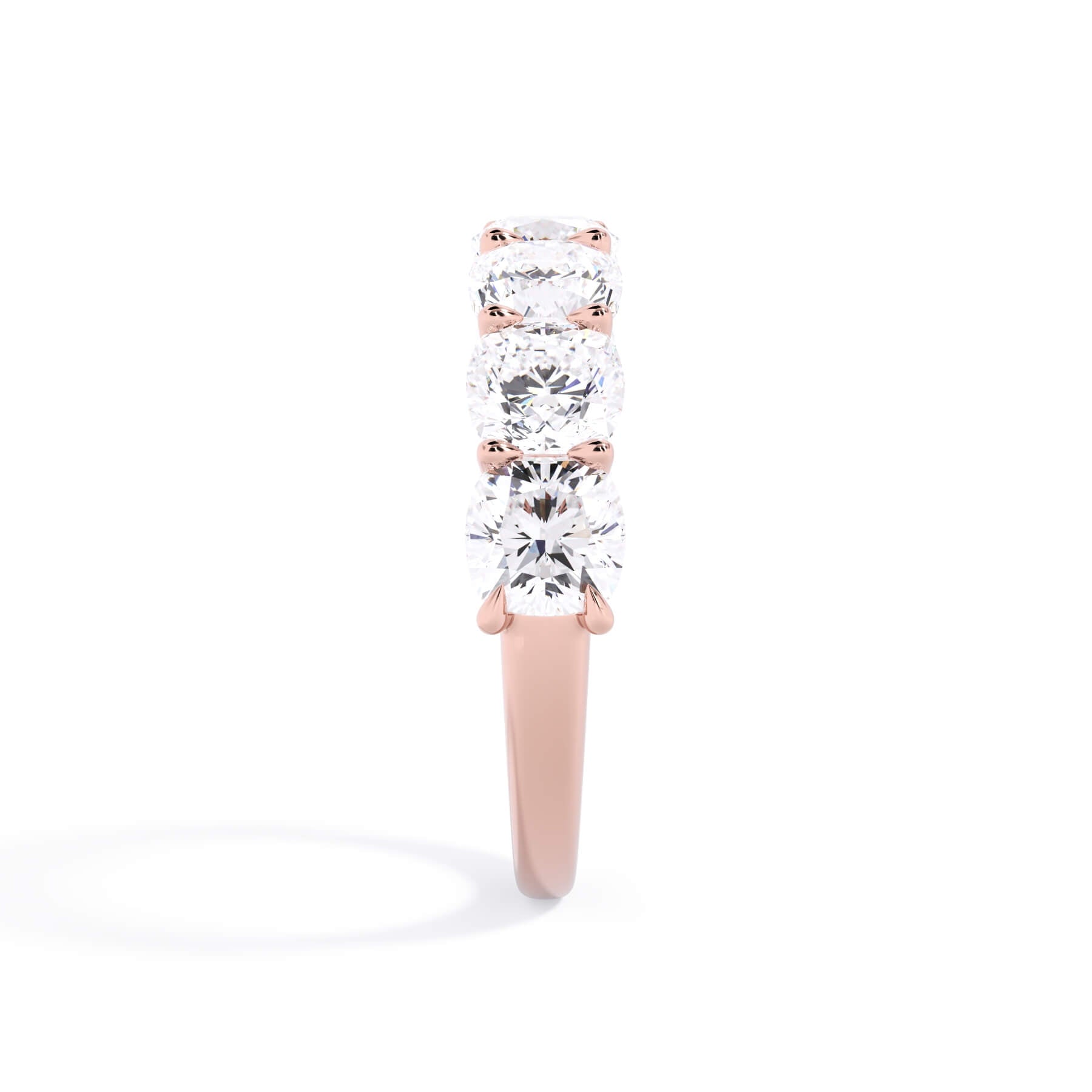 A picture of a seven stone diamond wedding ring with cushion cut diamonds that are U prong set in rose gold on a white background with a side profile view.