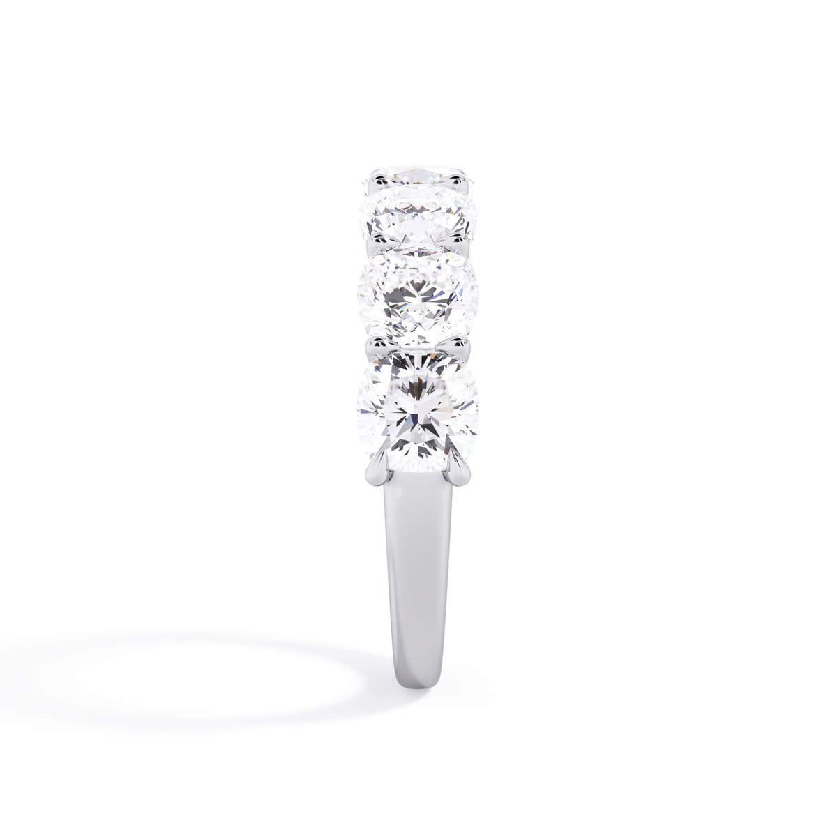 A picture of a seven stone diamond wedding ring with cushion cut diamonds that are U prong set in white gold or platinum on a white background with a side profile view.
