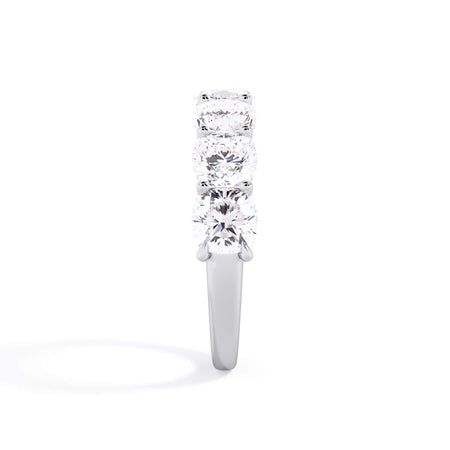 A picture of a seven stone diamond wedding ring with cushion cut diamonds that are U prong set in white gold or platinum on a white background with a side profile view.