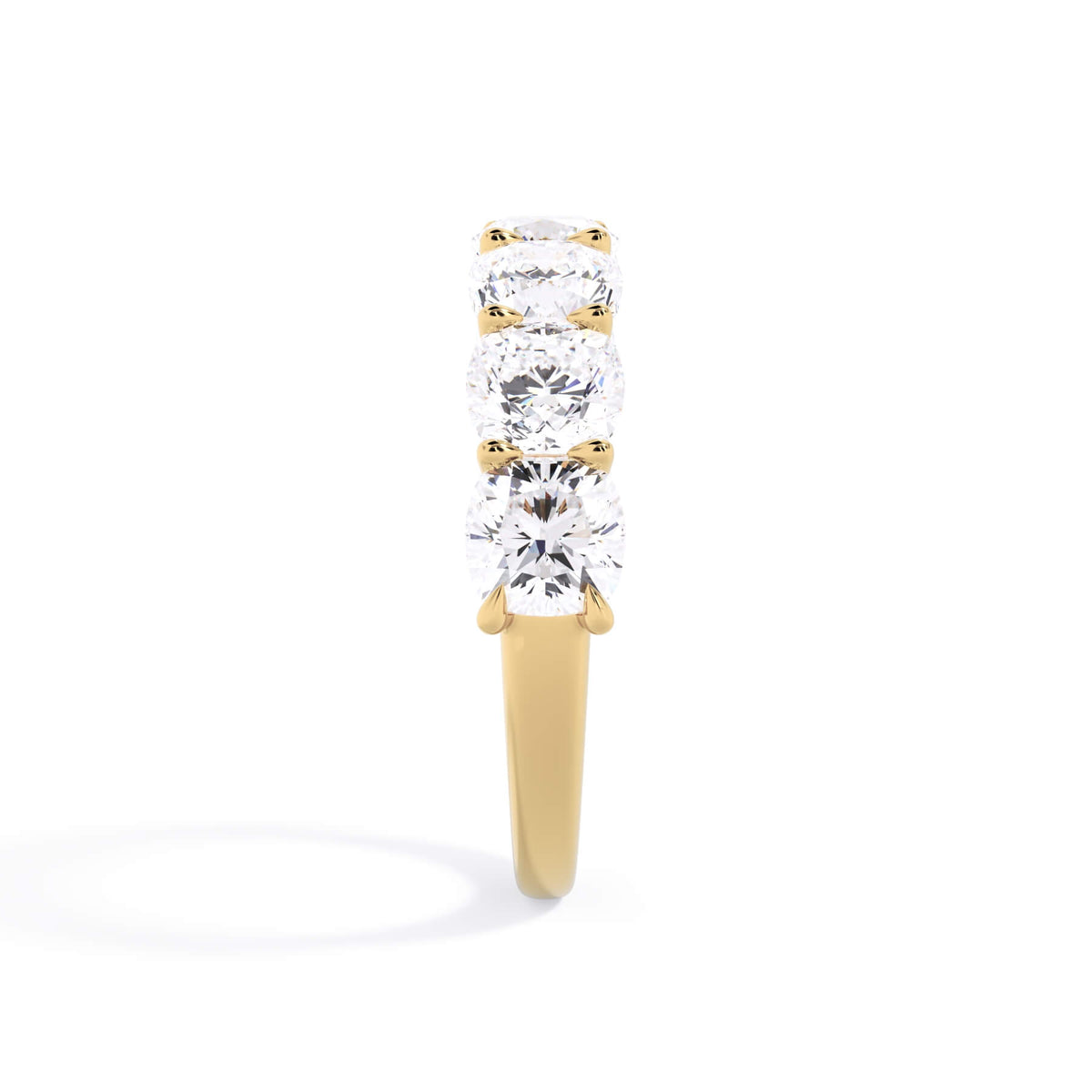 A picture of a seven stone diamond wedding ring with cushion cut diamonds that are U prong set in yellow gold on a white background with a side profile view.