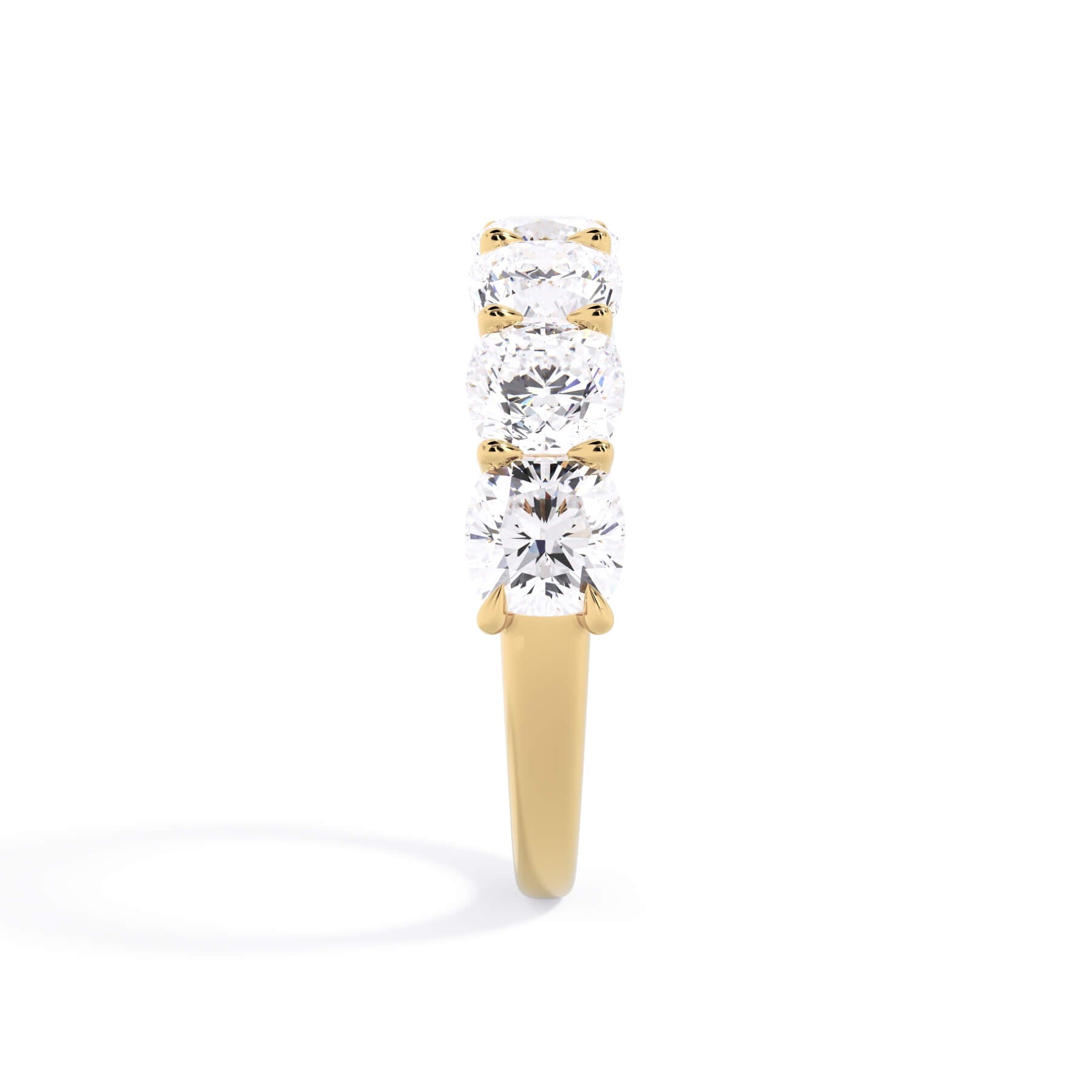 A picture of a seven stone diamond wedding ring with cushion cut diamonds that are U prong set in yellow gold on a white background with a side profile view.