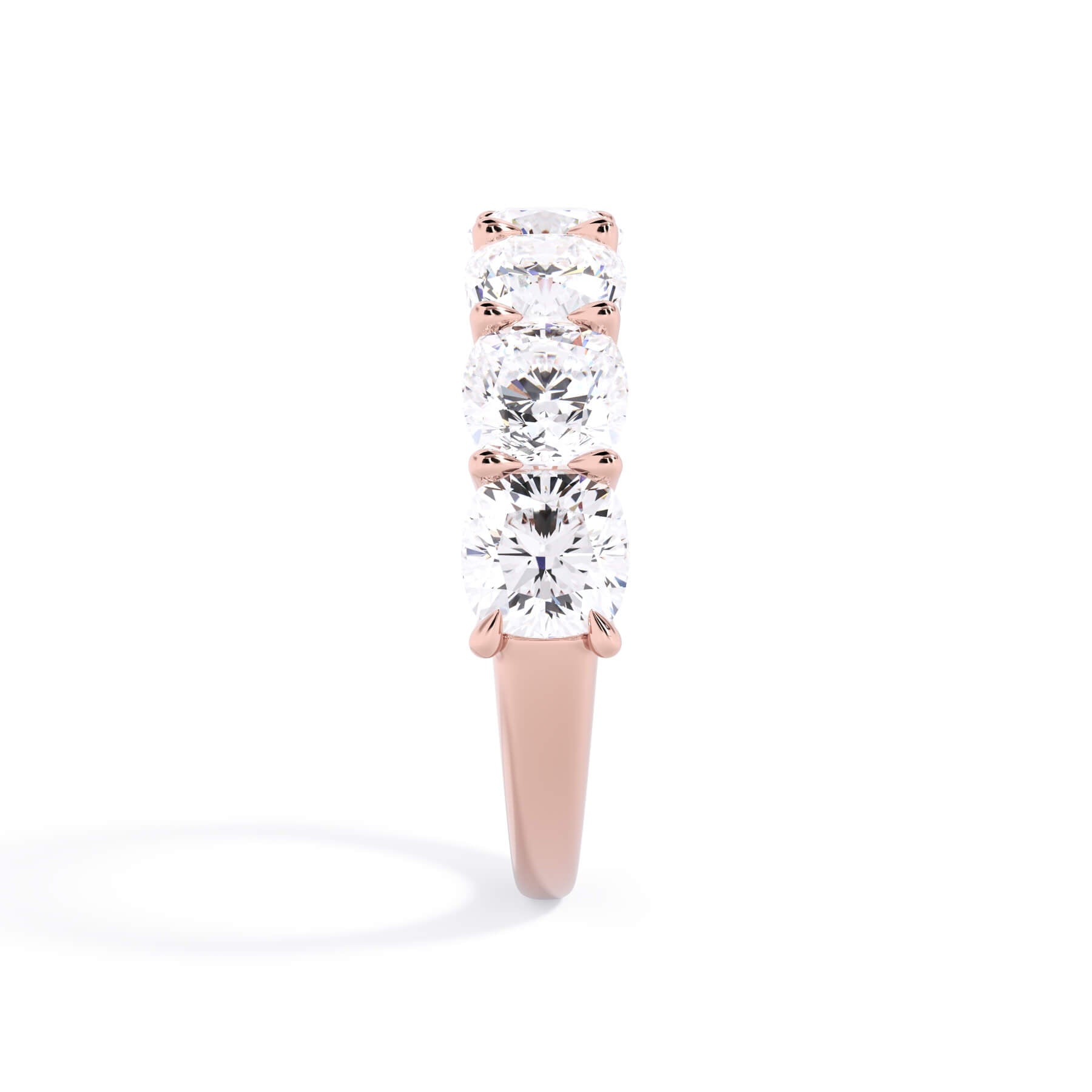 A picture of a seven stone diamond wedding ring with cushion cut diamonds that are U prong set in rose gold on a white background with a side profile view.