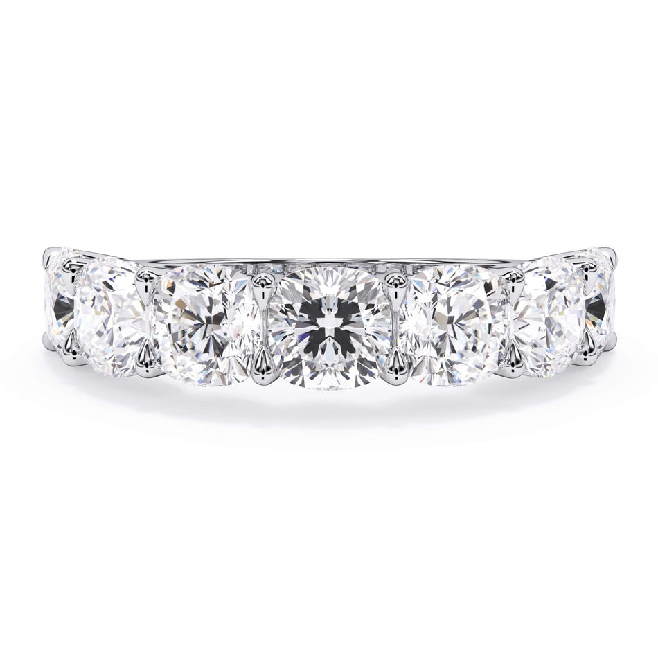 A picture of a seven stone diamond wedding ring with cushion cut diamonds that are U prong set in white gold or platinum on a white background with the ring facing forward, lying down.