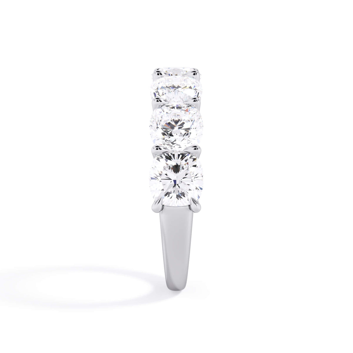 A picture of a seven stone diamond wedding ring with cushion cut diamonds that are U prong set in white gold or platinum on a white background with a side profile view.