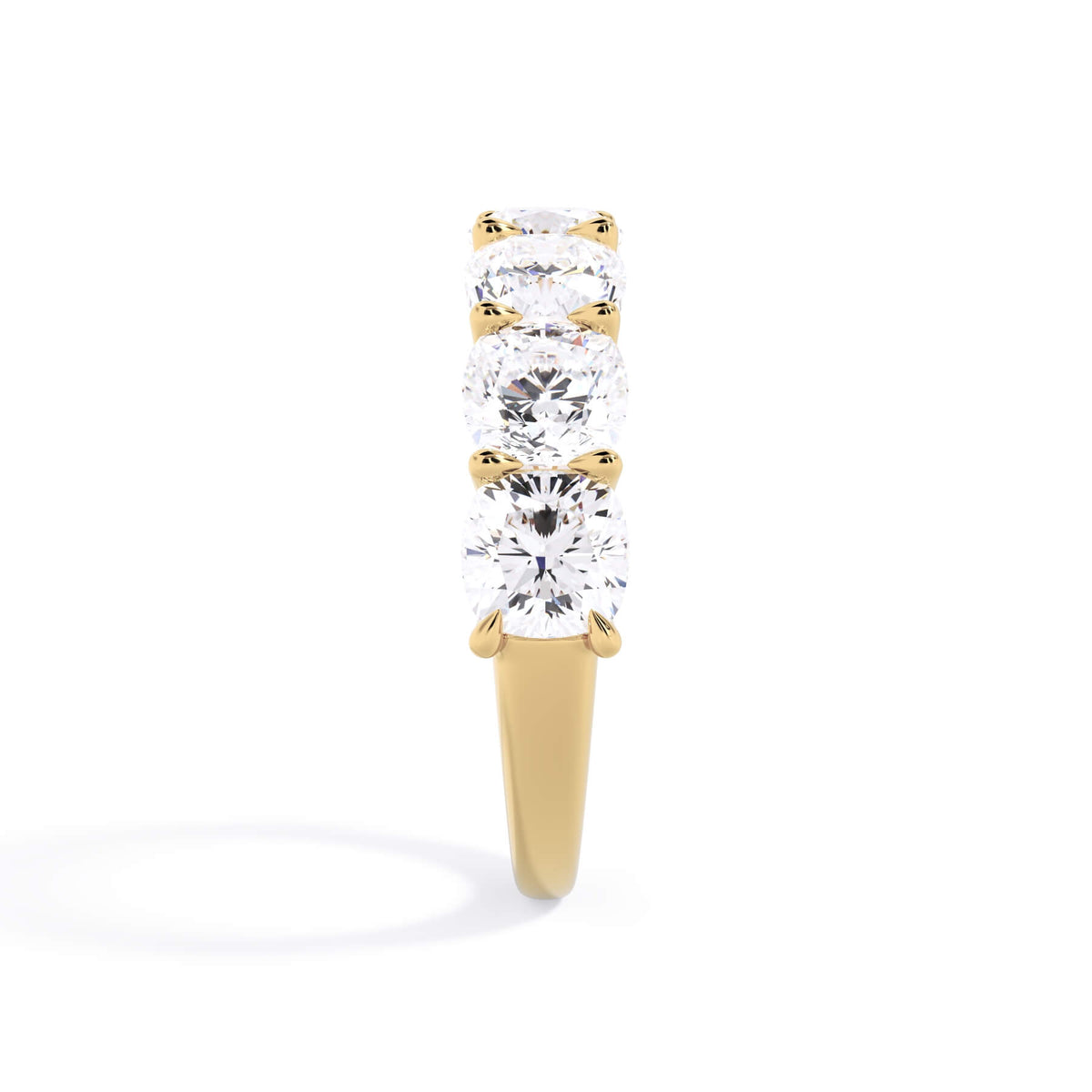A picture of a seven stone diamond wedding ring with cushion cut diamonds that are U prong set in yellow gold on a white background with a side profile view.