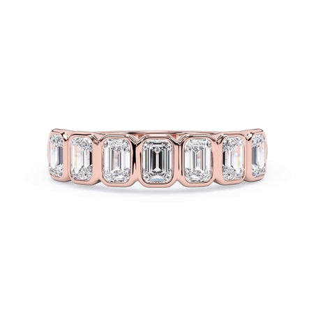 A picture of a seven stone diamond wedding ring with emerald cut diamonds that are bezel set in rose gold on a white background with the ring facing forward, lying down.