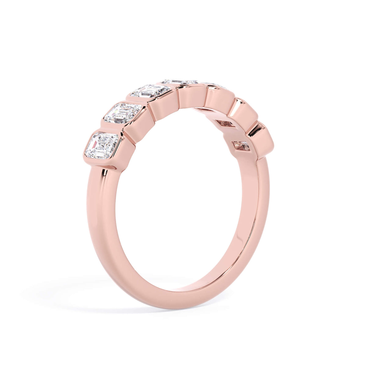 A picture of a seven stone diamond wedding ring with emerald cut diamonds that are bezel set in rose gold on a white background with a slightly angled, through the finger view.